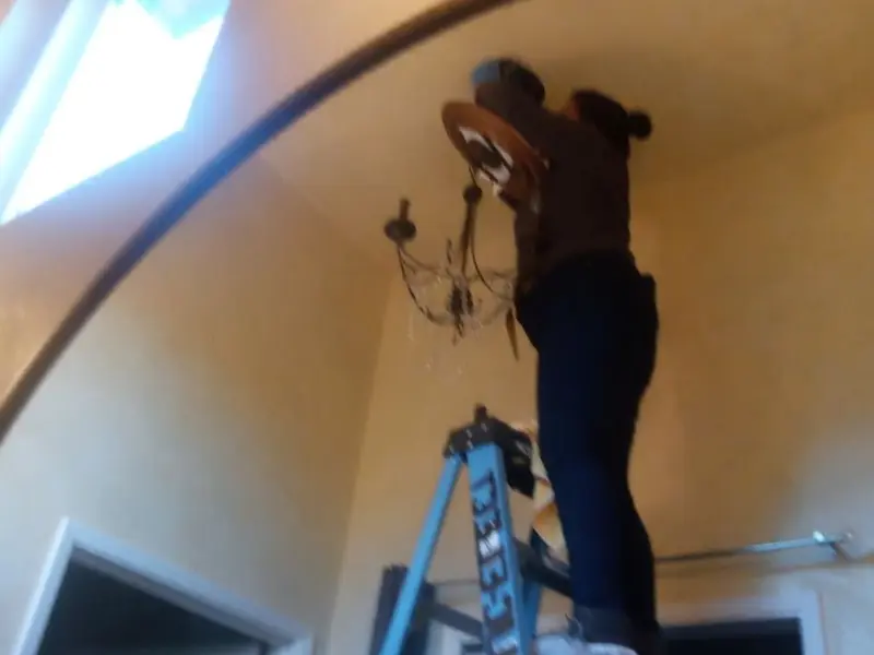 Electrician installing a chandelier in a Rancho Cordova residence